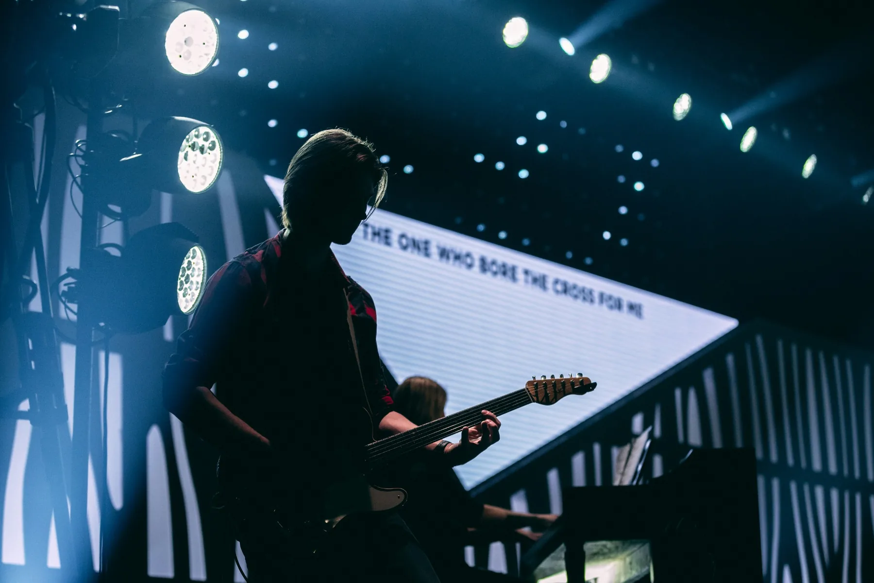 A guitarist playing under stage lighting